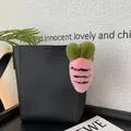 Pink plush carrot bag charm with black stripes and green top on a black tote bag - Pink