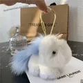 Macro view of fluffy white plush unicorn keychain with golden horn and metal clip - Sky Blue
