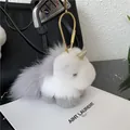 Detail of plush unicorn bag charm with fluffy grey fur and golden horn on leather bag - Light Gray
