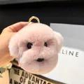 Gros plan d'un porte-clés chiot rose pelucheux avec texture douce et anneau doré - Rose Clair