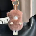 Detail of pink-brown mink fur lamb keychain with gold metal ring on a leather bag - Dusty Pink