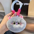 Close-up of grey plush cat keychain with fluffy fur, round eyes and blue woven strap - Dusty Pink