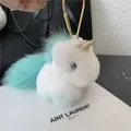Detail of plush unicorn keychain with gold hook and soft faux fur on a leather bag - Mint Green