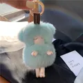 Cute light blue mink fur lamb keychain with golden ring on a silk background - Fresh Green