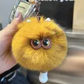 Nahaufnahme eines flauschigen orangefarbenen Monster-Schlüsselanhängers mit großen Augen - Camel