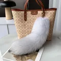 Detail of a large fluffy grey faux fur tail keychain on a luxury handbag - Natural Blue Fox