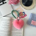 Close-up of fluffy pink heart-shaped faux fur keychain with woven lanyard on desk - Peach Pink