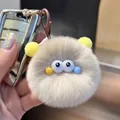 Close-up of a fluffy grey plush pompom keychain with cartoon eyes and pink spring buckle - Milk Tea