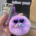Detailed view of a purple plush keychain with funny eyes and heart sunglasses on car keys - Purple