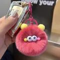 Close-up of a pink plush monster keychain with yellow ears attached to a car key - Berry Pink