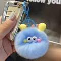 Detail shot of a soft blue fuzzy pompom keychain with cute cartoon eyes and metal hook - Blue