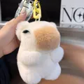 Handheld view of a plush capybara keychain made of real rabbit fur for car key accessories - Off White