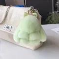 Gros plan d'un charme de lapin en peluche vert menthe avec nœud à pois sur un sac beige - Vert