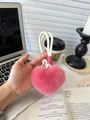Close-up of a pink plush heart keychain with a white braided rope on a cozy desk setup - Rose Pink