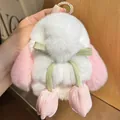 Close-up of white rabbit plush charm with pink ears and green ribbon on a bag - Light Pink
