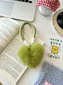 Detail van de lichtgroene pluche hart sleutelhanger met geweven koord op lifestyle-achtergrond - Avocadogroen