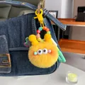 Detail of yellow plush monster keychain with colorful letter beads on a denim handbag - Yellow