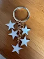 Porte-clés doré avec cinq pendentifs étoiles blanches sur fond de bois - Blanc