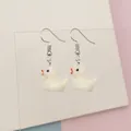Detail of cute white resin duck earrings hanging on a transparent display stand - White