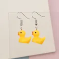 Close-up of cute yellow resin duck earrings with silver hooks on a soft pink background - Yellow