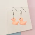 Close-up of cute peach pink resin duck earrings with detailed orange beak and silver hooks - Pink
