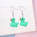 Detail of cute mint green resin duck earrings with silver hooks on an acrylic stand - Dark Green