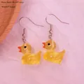 Detail showing size dimensions and resin texture of yellow duck dangle earrings - Luminous Ginger Yellow