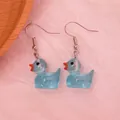 Detail of light blue resin duck earrings with silver hooks on pink background - Luminous Blue