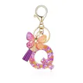Porte-clés lettre Q en résine avec fleurs séchées mauves, papillon doré et pompon - Lettre Q-Thème Floral Violet Orange (QS2157)