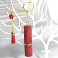 Dettaglio di un portachiavi a rossetto rosso con strass, ciondolo a fiore e nappa - Rosso