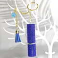 Detail showing blue rhinestone-encrusted spray bottle with golden keychain and tassel - Blue