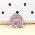 Vue macro du pendentif lettre Q en strass rose avec anneau doré sur une surface - Lettre Q en Strass Rose (Q)