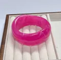 Wide rose pink resin bangle with white marble texture on a wooden jewelry display tray - Rose Red