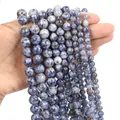 Macro detail of blue and white sodalite gemstone beads in various sizes on a white surface - Blue Spot Jasper