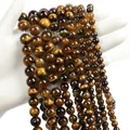 Natural tiger eye stone round beads with golden brown stripes held in hand - Tiger Eye