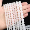 Multiple sizes of smooth translucent white agate beads held by hand for size comparison - Agate