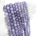 Strands of purple round natural stone beads with white texture held by hand for jewelry - Lavender Chalcedony