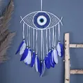 Bohemian Evil Eye dream catcher with white ribbons and blue feathers on navy wall - Blue & White Evil Eye