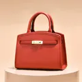 Elegant red leather handbag with gold metal buckle on display for office and daily wear - Red