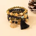 Macro detail of bohemian layered wooden beads with Tree of Life charm and black tassel - Black