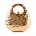 Makro-Detail der goldenen Abendtasche mit einzigartiger metallischer Wellenstruktur - Gold