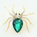 Close-up of golden spider brooch with a pear-cut green gemstone and sparkling crystals - Luxury Rhinestone Spider Brooch
