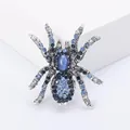 Macro shot of spider brooch with blue rhinestones and cat eye stone on white stand - Cool Tone Spider Design Rhinestone Brooch