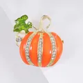 Macro shot of orange enamel pumpkin brooch with white crystals on a gold base - Enamel Drip Rhinestone Pumpkin Brooch