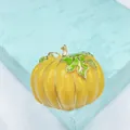 Close-up of yellow enamel pumpkin brooch with green leaves on a light blue gift box - Glossy Enamel Pumpkin Design Brooch
