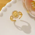 Detail of gold-plated Virgin Mary ring with zirconia stones on a white ceramic plate - Hollow Pattern Virgin Mary Style