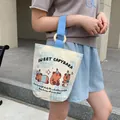 Canvas bucket bag featuring light blue grid, cartoon capybaras and wood ring handle - Capybara Sweet Dream