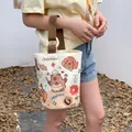 Cream canvas bucket bag with capybara print and brown handle featuring a wooden ring - Happy Capybara