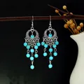 Détail de boucles d'oreilles bohèmes argentées avec perles turquoise sur une branche - Bleu (Gland bohémien)