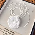 Gros plan d'un collier choker fleur de camélia en satin blanc dans un coffret cadeau chic - Fleur en Tissu Blanche (25453D)